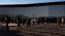 Migrants walk in a line to a Border Patrol transport van at the U.S.-Mexico border fence near Lukeville, Arizona, U.S., December 24, 2023.   REUTERS/Rebecca Noble