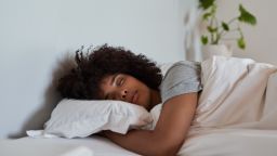 Young African woman lying fast asleep in her comfortable bed at home in the early morning