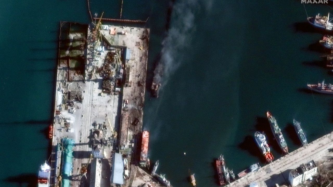 An aerial image captured by Maxar shows the warship (center) detached from the port and billowing with smoke.