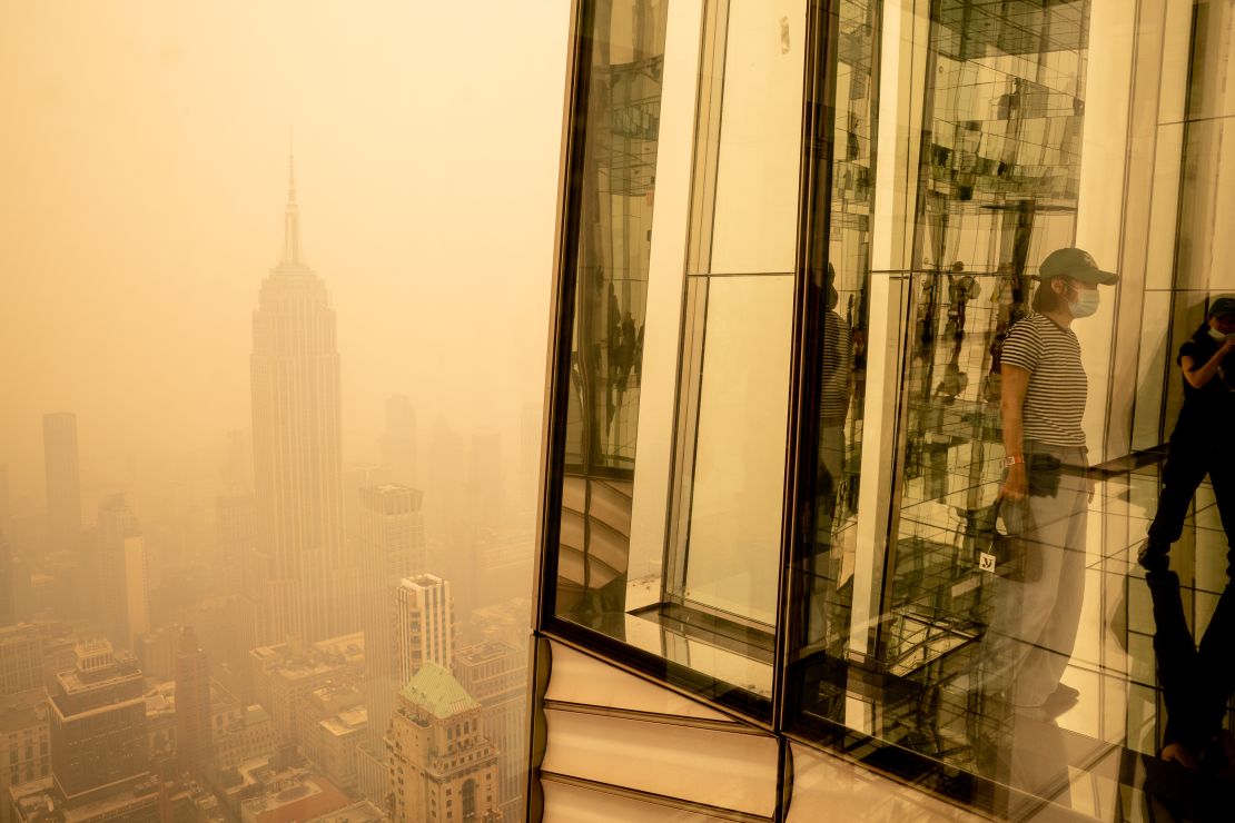 Visitors at Summit One Vanderbilt look out at a smoke-shrouded Manhattan as wildfires in Canada continue to blanket the city on June 7, 2023 in New York City.