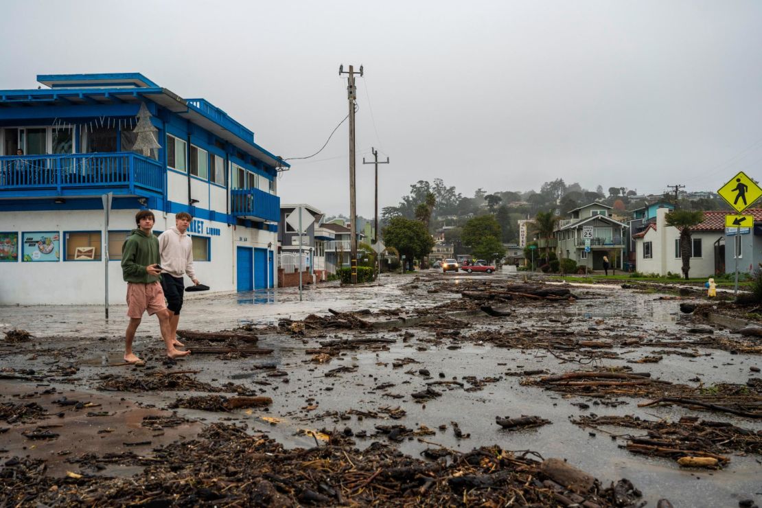 Two men walk through ocean debris in the Rio Del Mar neighborhood of Aptos, Thursday, Dec. 28, 2023. (AP Photo/Nic Coury)