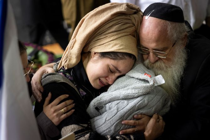 The wife of IDF soldier Sergeant Elisha Yehonatan Lober, who was killed in southern Gaza, holds their baby during his funeral at the Mount Herzl military cemetery in Jerusalem on December 27.