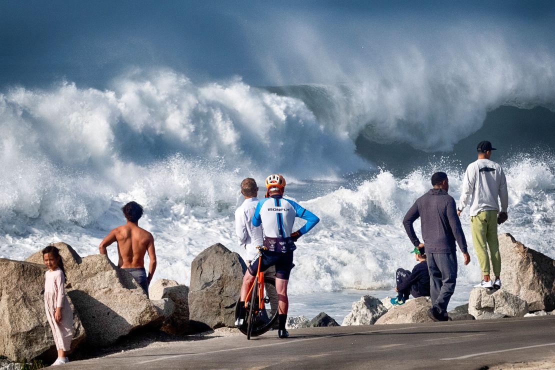 Beachgoers watch as huge surf pounds the coast, in Manhattan Beach, Calif., Dec. 28, 2023. (AP Photo/Richard Vogel)