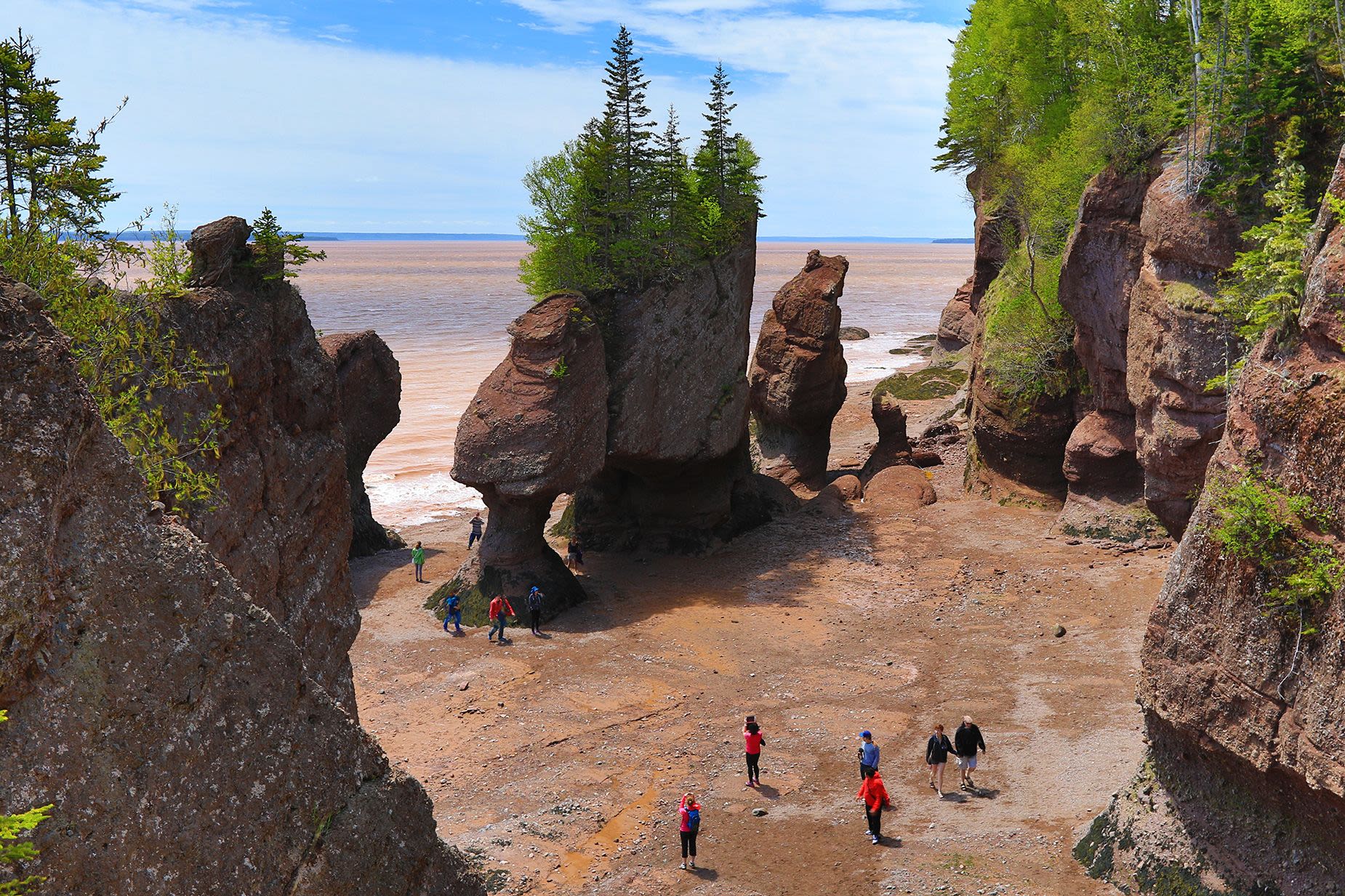 ETKAGE Bay of Fundy Hopewell Rocks beach at low tide with tourists walking beach, New Brunswick, Canada