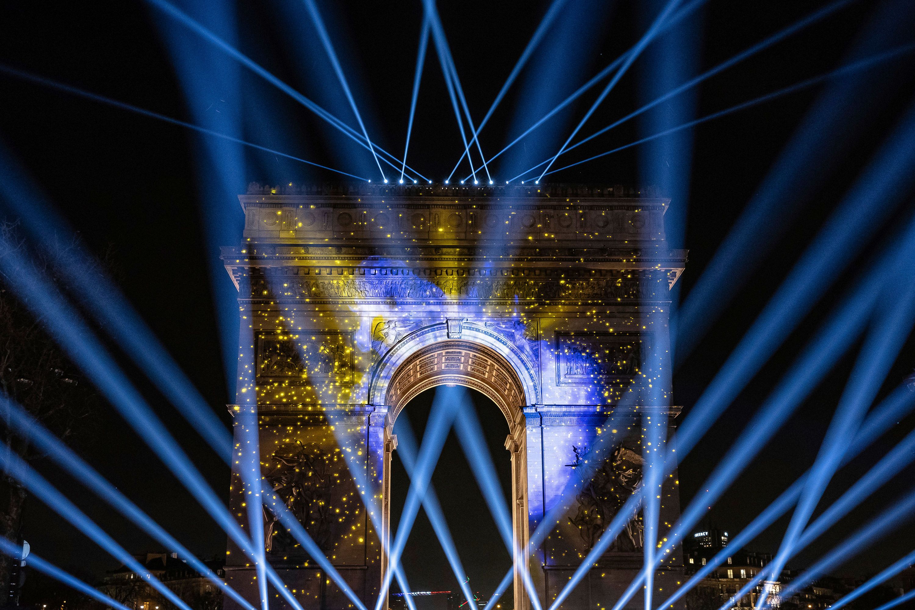 A light show is projected on the Arc de Triomphe in Paris.