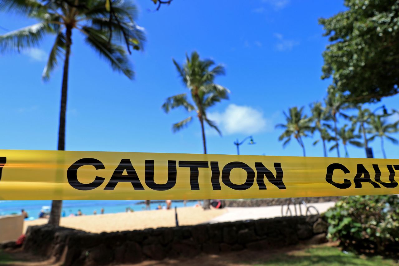 Yellow caution tape is wrapped across an area of Waikiki, after all public parks and recreation areas were closed on March 20 in Honolulu. 