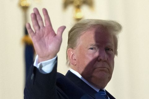 President Donald Trump waves from the Blue Room Balcony upon returning to the White House Monday, October 5, in Washington, after leaving Walter Reed National Military Medical Center.