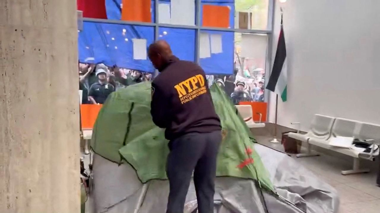 A NYPD officer removes a tent set up by pro-Palestinian protesters inside a building of the Fordham University,  in New York on Wednesday, May 1.