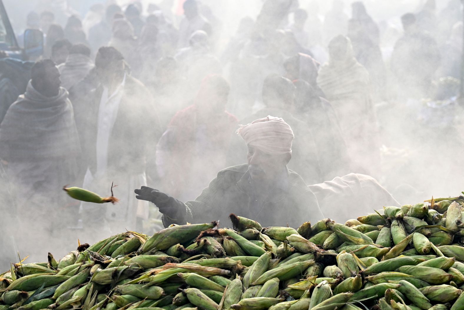 A vendor prepares to load roasted corn onto carts at a market in Lahore, Pakistan, on Thursday, January 9.