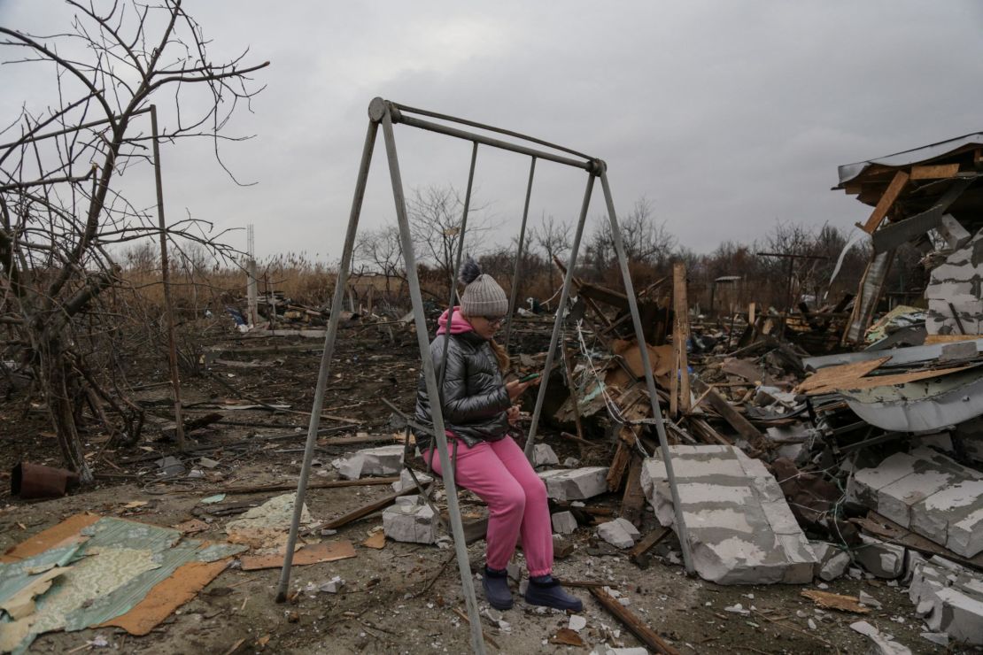 Una niña usa su teléfono móvil mientras está sentada en una hamaca en un complejo de casas residenciales que sufrieron graves daños durante un ataque con drones rusos, en medio del ataque ruso a Ucrania, en Odessa, Ucrania, el 1 de enero de 2024. REUTERS/Serhiy Smolentsev