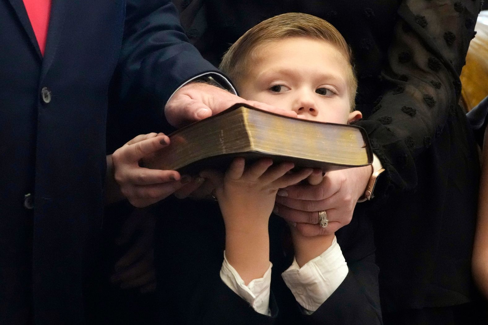 Casper Rhodes holds up his family's Bible as his father, Mississippi state Sen. Brian Rhodes, is sworn in at the State Capitol in Jackson on Tuesday, January 2.