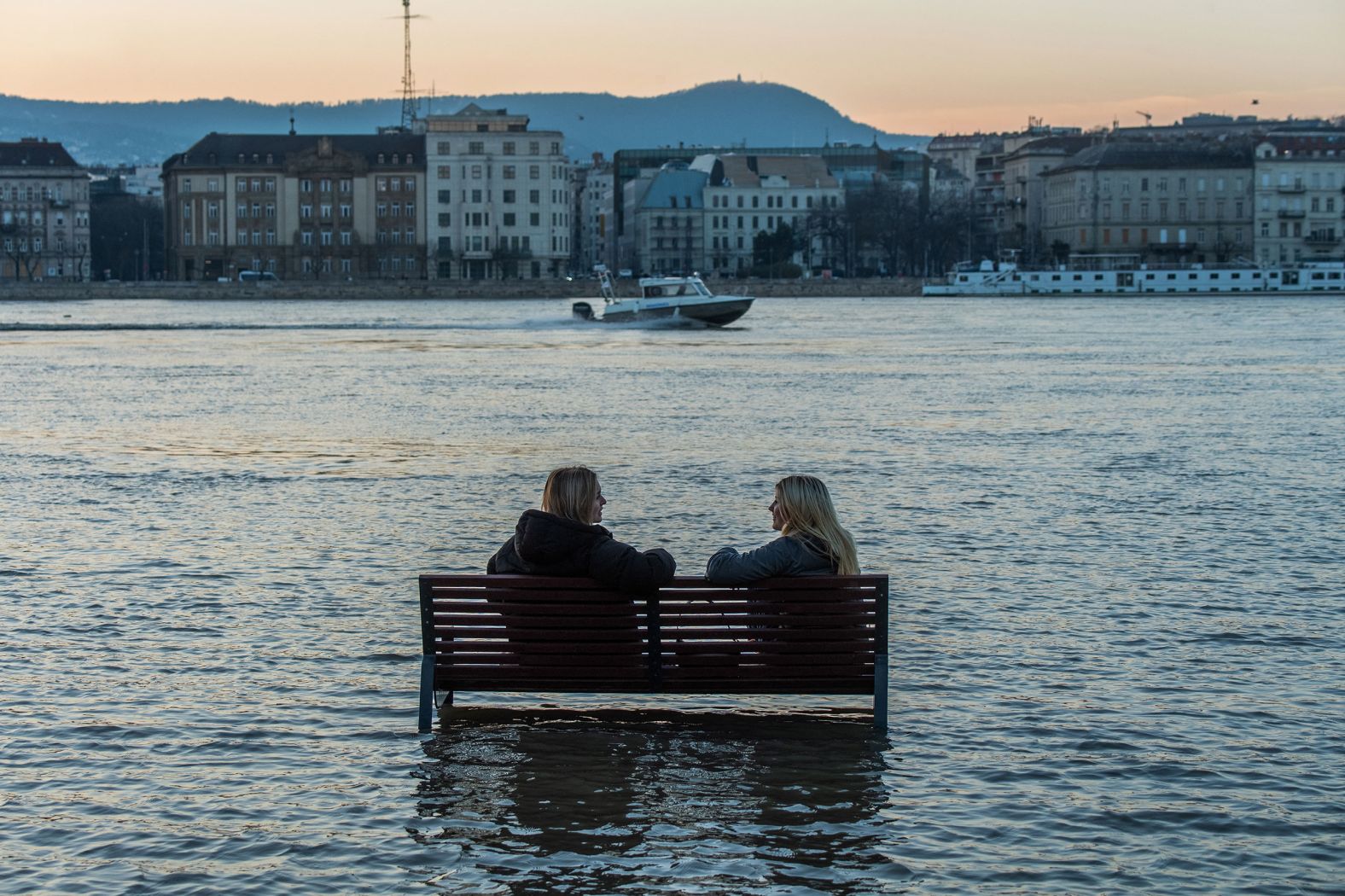 Women sit on a bench surrounded by floodwater in Budapest, Hungary, on Thursday, December 28. The Danube River burst its banks because of unusually wet and warm weather.