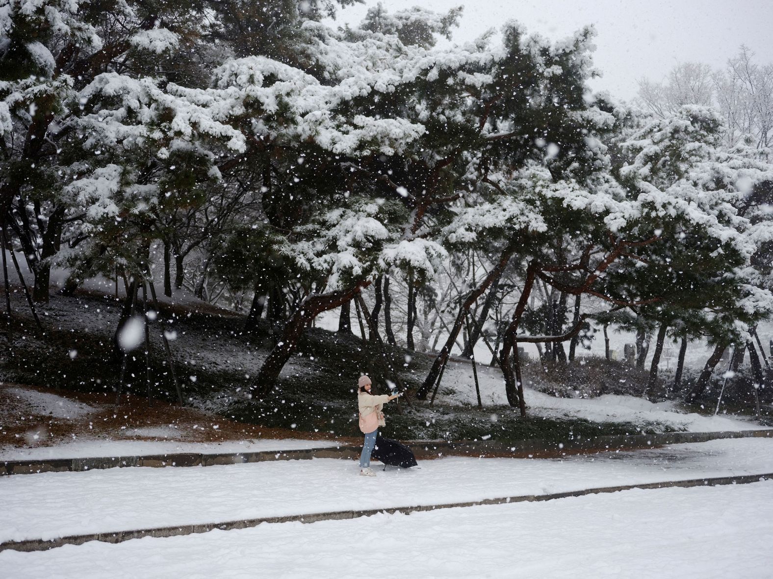 A woman takes a selfie at a snowy park in Seoul, South Korea, on Saturday, December 30.