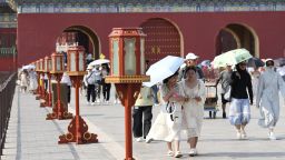 Tourists shield themselves from the sunshine with umbrellas at the Temple of Heaven in Beijing, capital of China, June 23, 2023.