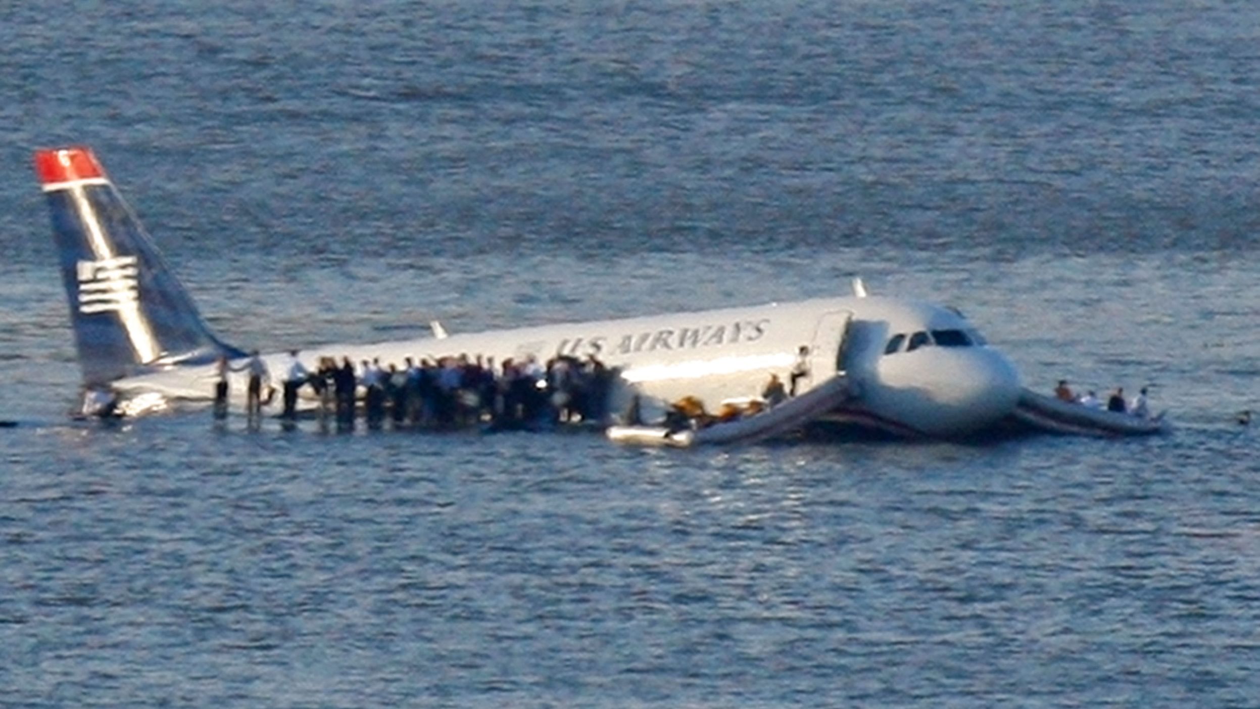 Passengers stand on the wings of a U.S. Airways plane as a ferry pulls up to it after it landed in the Hudson River in New York, January 15, 2009.  Local media said the plane was an Airbus with 146 passengers and five crew which had just taken off from La Guardia Airport and was trying to return after apparently striking a flock of birds.   REUTERS/Brendan McDermid (UNITED STATES)  FOR BEST QUALITY ALSO SEE: GF2E51F1M4V01