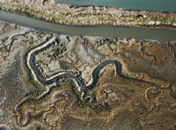 Slowly but surely, as man-made levees used for harvesting salt have been removed, tidal systems have infiltrated once more, and the bright colors have dissipated. "Green ribbons of life" seep back into the ponds, says Boissevain. (Image title: Tidal Salt Marsh, Aerial, 2017)