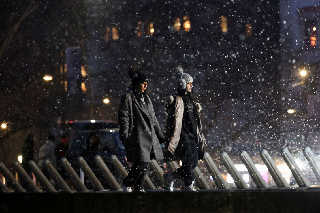 People walk as snow falls in New York City, U.S., January 6, 2024. REUTERS/Andrew Kelly