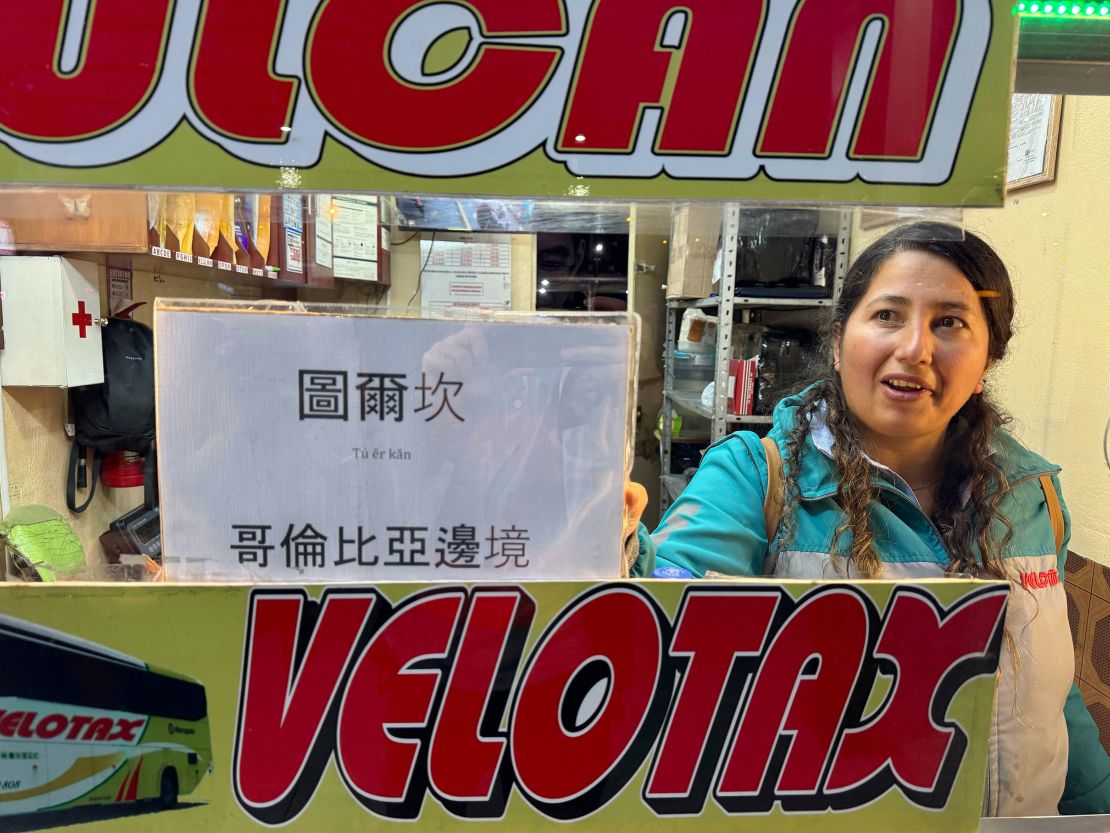 A ticket agent in Quito holds up a sign written in Chinese for the bus to "Tulcan at the Colombian border."