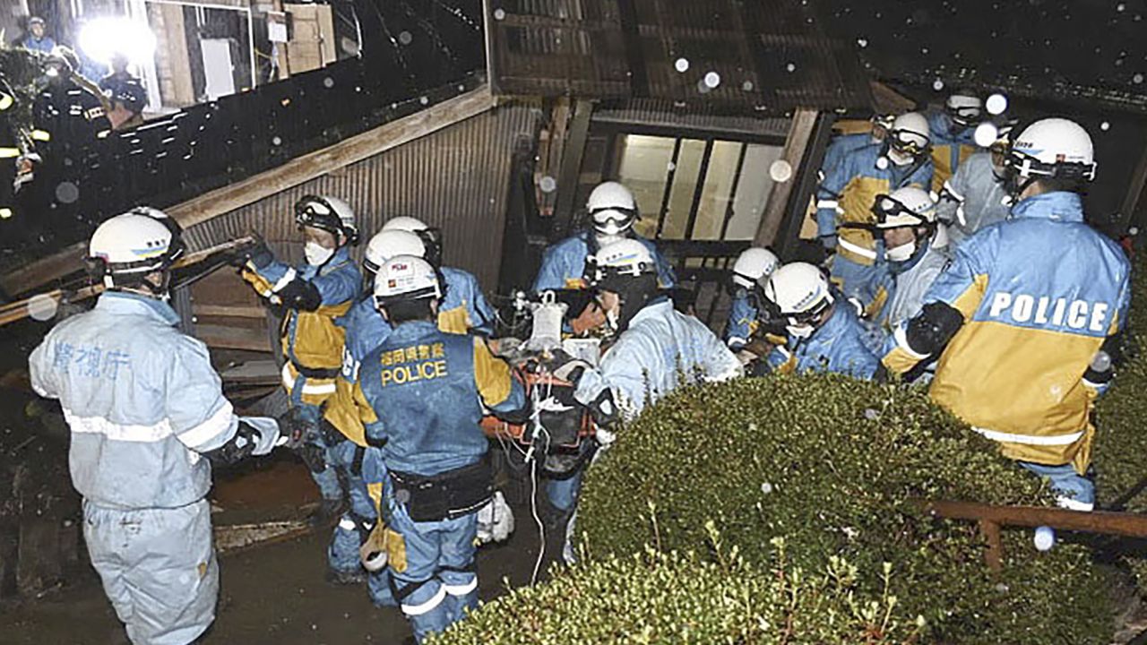 In this photo released by Metropolitan Police Department via Kyodo News, police officers rescue a woman from a collapsed house in Suzu, Ishikawa prefecture, Japan, Saturday, Jan. 6, 2024. The woman in her 90s was pulled alive from the collapsed house late Saturday, 124 hours after a major quake slammed the region, killing scores of people, toppling buildings and setting off landslides. (Metropolitan Police Department/Kyodo News via AP)