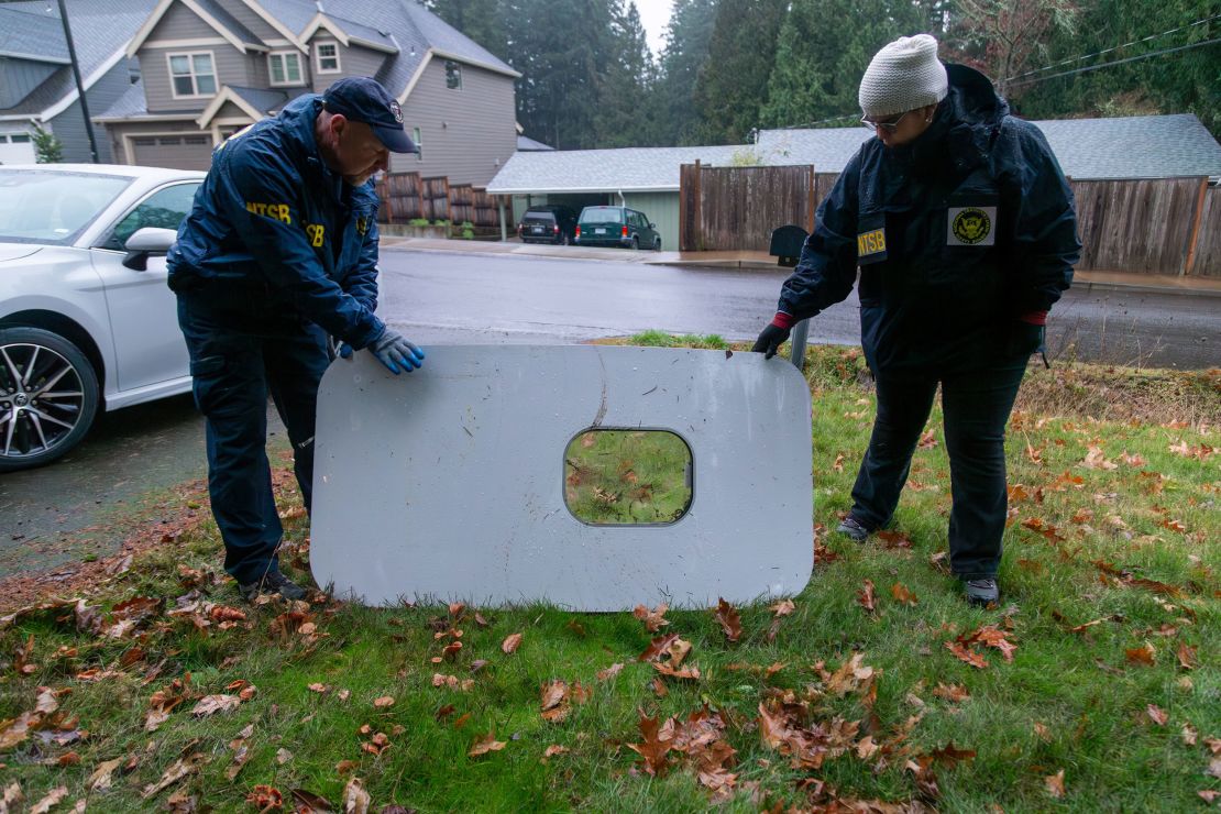 National Transportation Safety Board officials retrieve the missing door plug from Alaska Airlines flight 1282, the Boeing 737 MAX 9 that experienced a rapid decompression on Friday over Portland, Oregon.  NTSB handout images