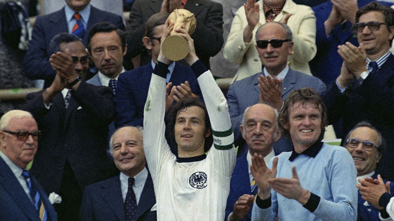 FILE - In this July 7, 1974 file photo, West Germany captain, Franz Beckenbauer, holds up the World Cup trophy after his team defeated the Netherlands by 2-1, in the World Cup soccer final at Munich's Olympic stadium, in West Germany. Applauding at right, German goalkeeper Josef "Sepp" Maier. On this day: West Germany wins its second World Cup after defeating the much-fancied Dutch. (AP Photo/File)