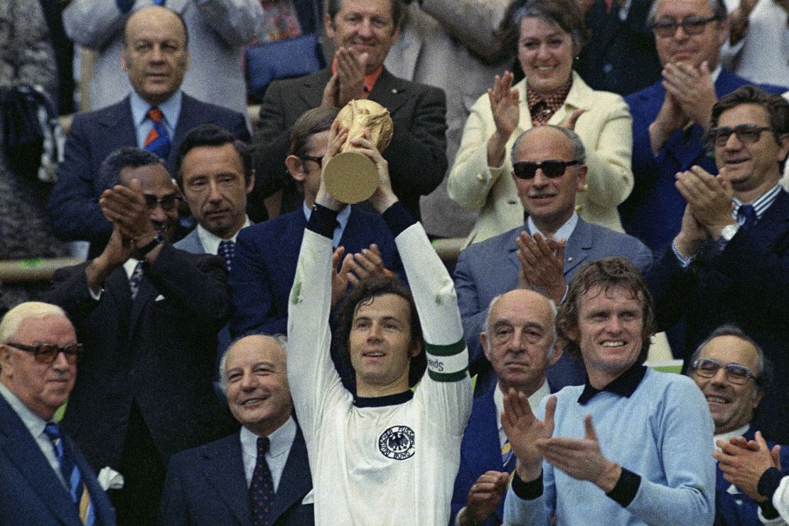 FILE - In this July 7, 1974 file photo, West Germany captain, Franz Beckenbauer, holds up the World Cup trophy after his team defeated the Netherlands by 2-1, in the World Cup soccer final at Munich's Olympic stadium, in West Germany. Applauding at right, German goalkeeper Josef "Sepp" Maier. On this day: West Germany wins its second World Cup after defeating the much-fancied Dutch. (AP Photo/File)