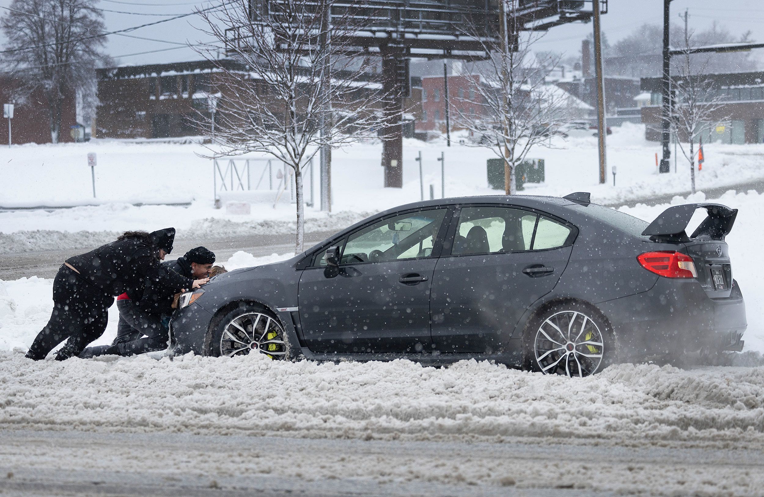 People in Des Moines help push a vehicle back onto the road after it became stuck in the snow on Tuesday.