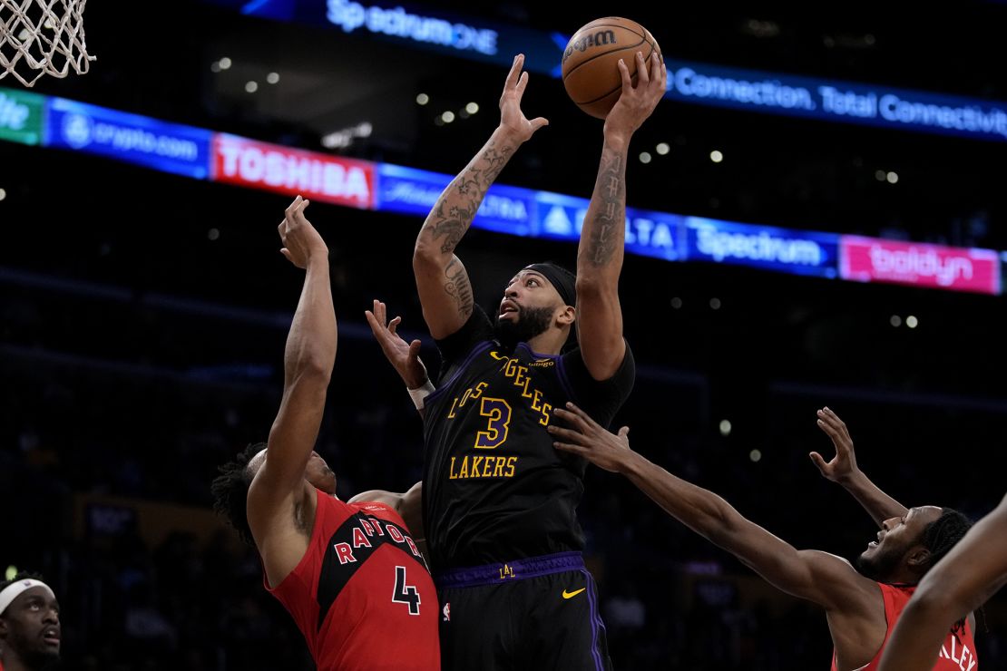 Los Angeles Lakers forward Anthony Davis (3) shoots against Toronto Raptors forward Scottie Barnes (4) and guard Immanuel Quickley (5) during the second half of an NBA basketball game in Los Angeles, Tuesday, Jan. 9, 2024. (AP Photo/Ashley Landis)