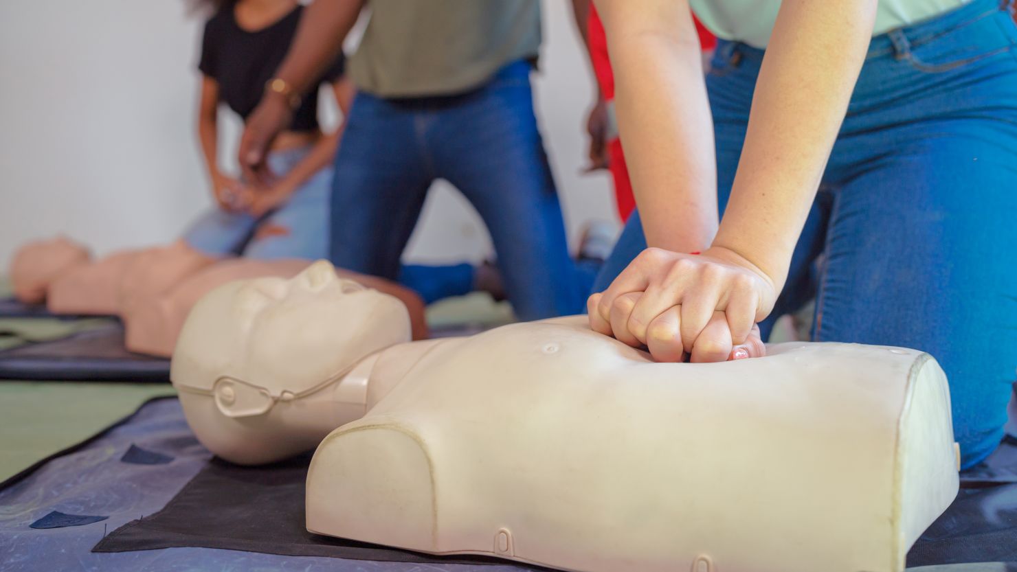 Hands Of A trainee doing chest compression during defibrillator CPR Training. - stock photo