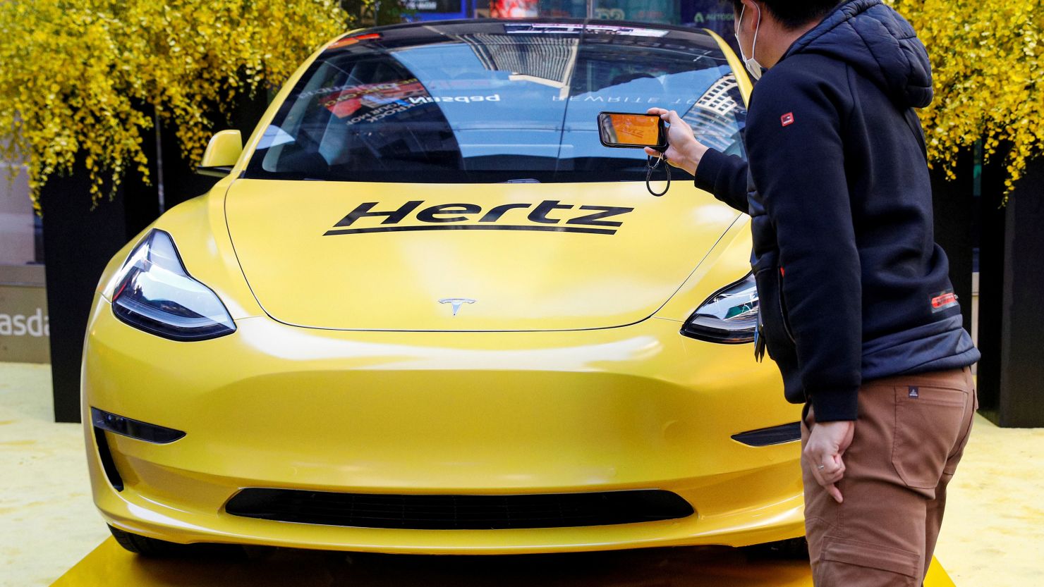 A man photographs a Hertz Tesla electric vehicle displayed during the Hertz Corporation IPO at the Nasdaq Market site in Times Square in New York City, U.S., November 9, 2021. REUTERS/Brendan McDermid