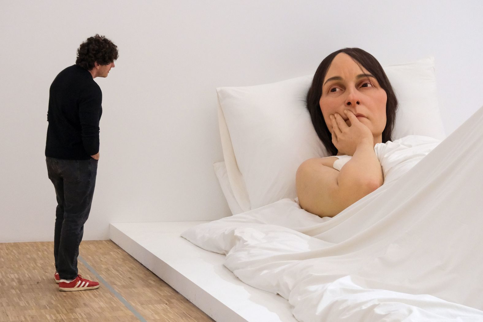 A visitor at the Triennale di Milano, a museum in Milan, Italy, looks at Ron Mueck's "In Bed" on Tuesday, January 9.