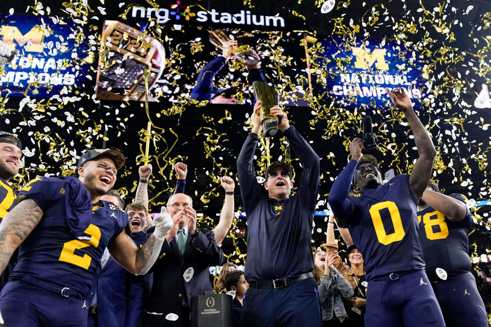 Michigan head coach Jim Harbaugh lifts the trophy as he and his team celebrate <a href="index.php?page=&url=https%3A%2F%2Fwww.cnn.com%2F2024%2F01%2F08%2Fsport%2F2024-cfp-national-championship-michigan-wolverines-washington-huskies-spt-intl%2Findex.html" target="_blank">winning the College Football Playoff</a> on Monday, January 8. Michigan defeated Washington 34-13 to win its first national title since 1997.