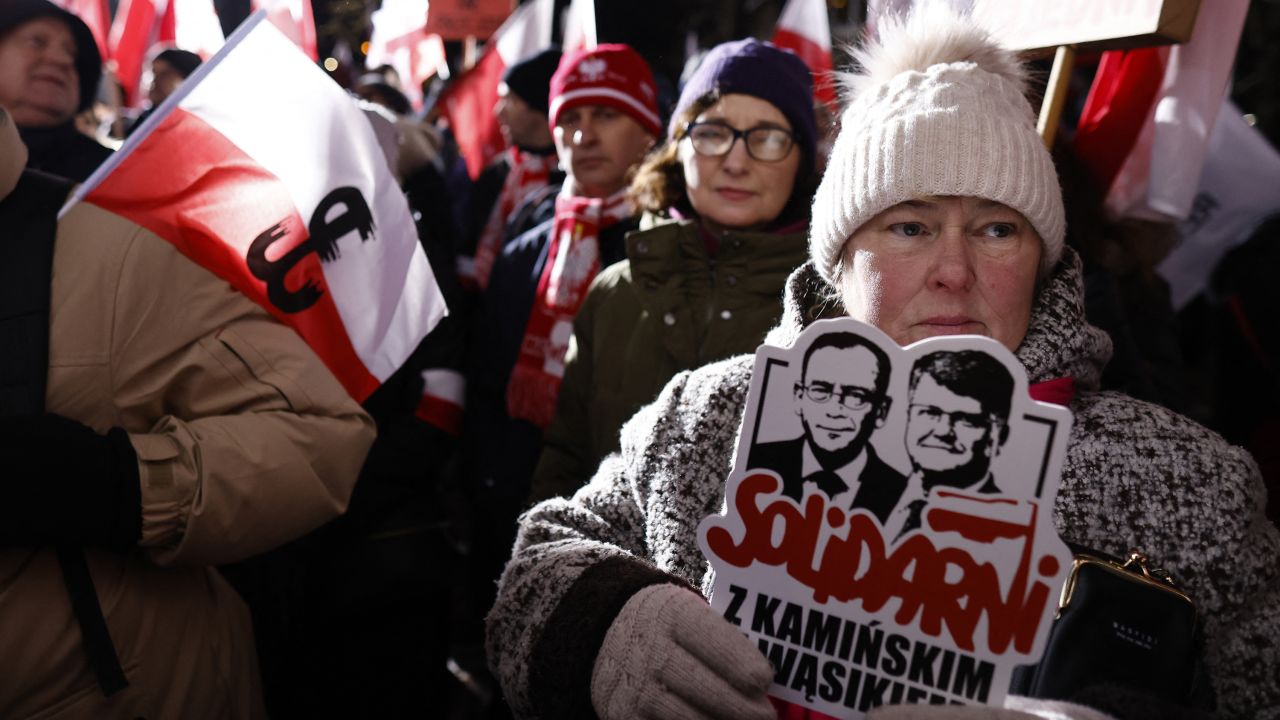 A woman holds a sign reading "Solidarity with Kaminski and Wasik" to protest in front of the Polish Parliament, Warsaw, January 11, 2024, during a demonstration in support of former Interior Minister Mariusz Kaminski and his deputy Maciej Wasik after their arrest. Polish President Andrzej Duda said he would pardon two populist ex-lawmakers who were arrested at his residence. Police detained prominent Law and Justice (PiS) politicians Mariusz Kaminski and Maciej Wasik at the presidential palace, where they sought refuge after being sentenced for overstepping their authority. (Photo by Wojtek Radwanski / AFP) (Photo by WOJTEK RADWANSKI/AFP via Getty Images)