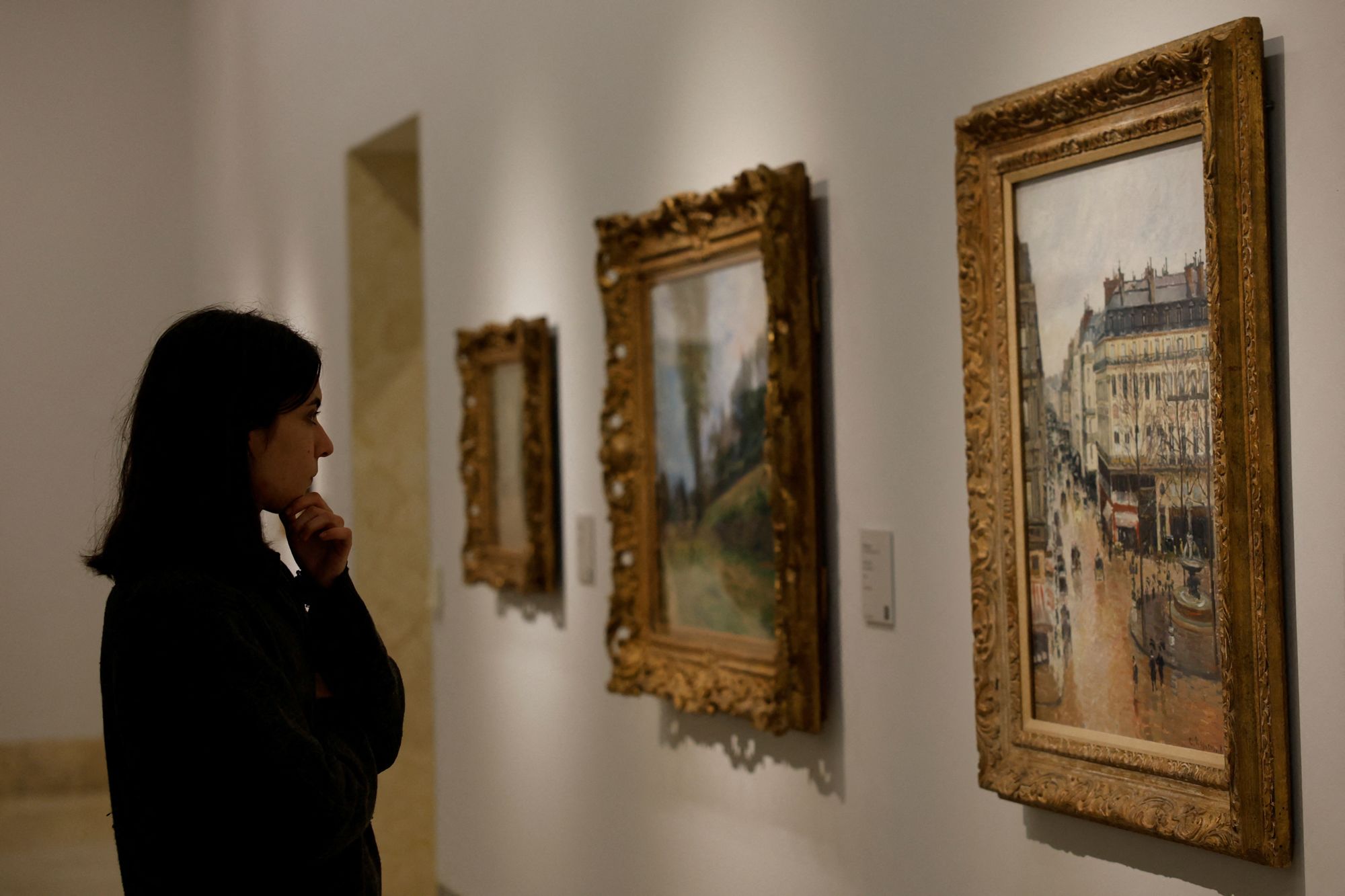 A visitor looks at Camille Pissarro's 1897 "Rue Saint-Honore in the Afternoon. Effect of Rain" at Thyssen-Bornemisza museum in Madrid, Spain, January 10, 2024. REUTERS/Susana Vera
