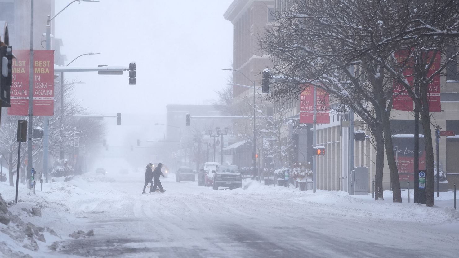 Pedestrians cross the street in snowy conditions Friday, Jan. 12, 2024, in Des Moines, Iowa. (AP Photo/Abbie Parr)