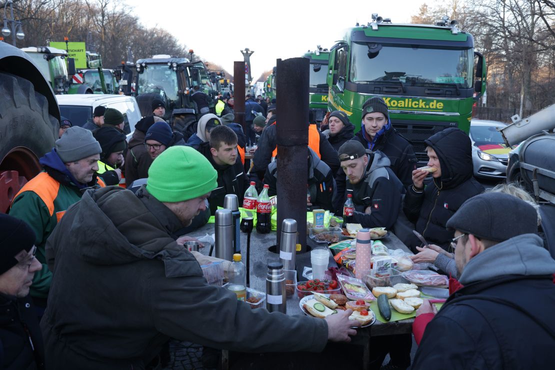 BERLIN, GERMANY - JANUARY 08: Protesting farmers have breakfast among their tractors and trucks while blocking Strasse des 17. Juni street on the first day of a week of protests on January 08, 2024 in Berlin, Germany. Farmers are protesting across Germany this week against proposed government measures that would reduce federal benefits for the agricultural sector. While the coalition government recently stepped back from some of the measures, including a proposed taxation of agricultural vehicles and cutting agricultural fuel subsidies, farmers have vowed to press on with their protests in order to stop any measures from being enacted at all. The government is seeking to save EUR 100 million in its agriculture budget. (Photo by Sean Gallup/Getty Images)