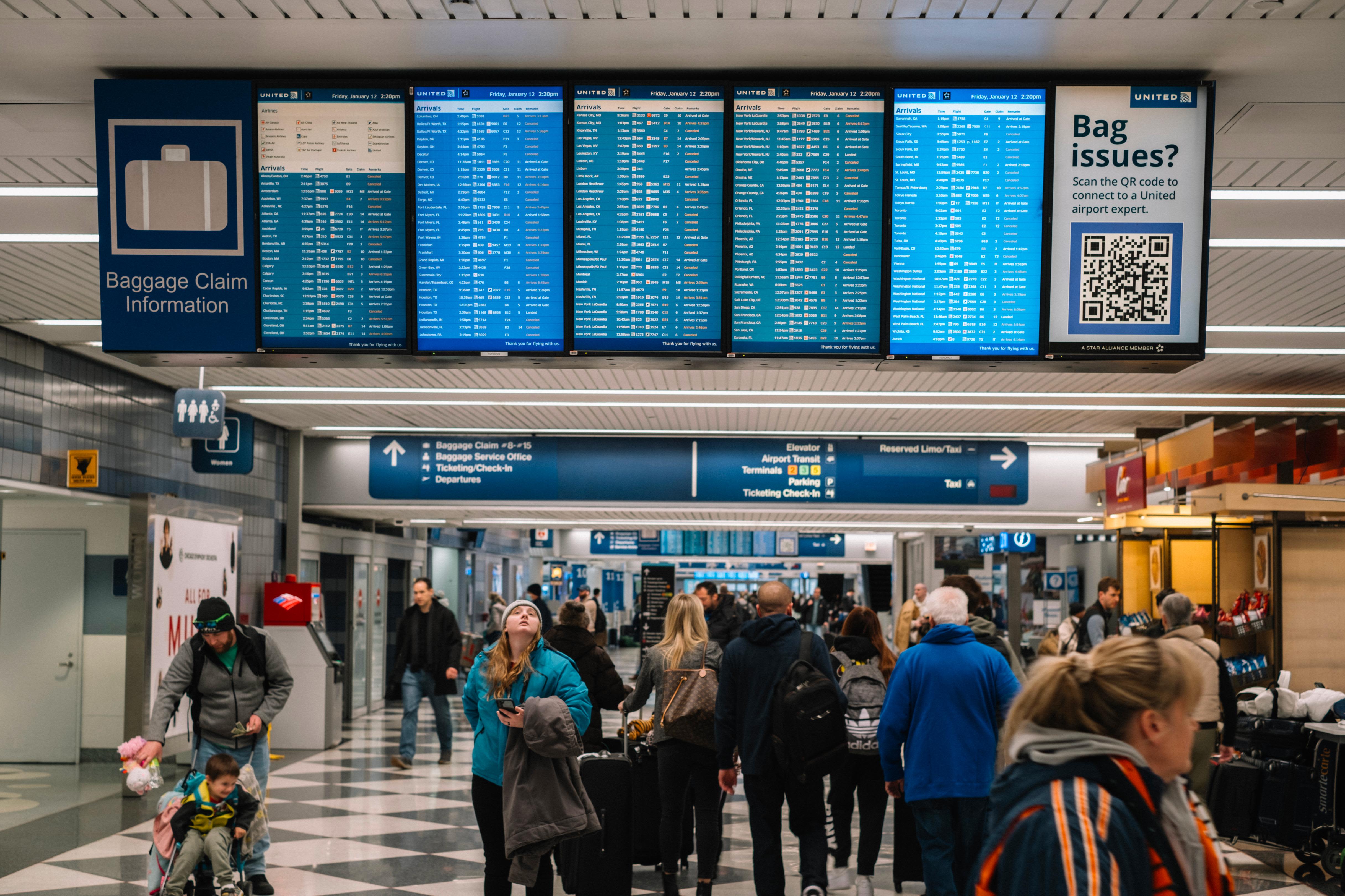 Travelers check their flight status at O'Hare Airport on Friday, January 12, in Chicago. More than 2,000 flights have been canceled nationwide due to a large winter storm bringing blizzard conditions.