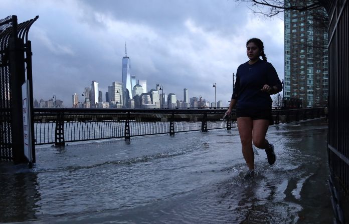Water from the Hudson River overflows at high tide as a woman jogs in Jersey City, New Jersey, on January 13.