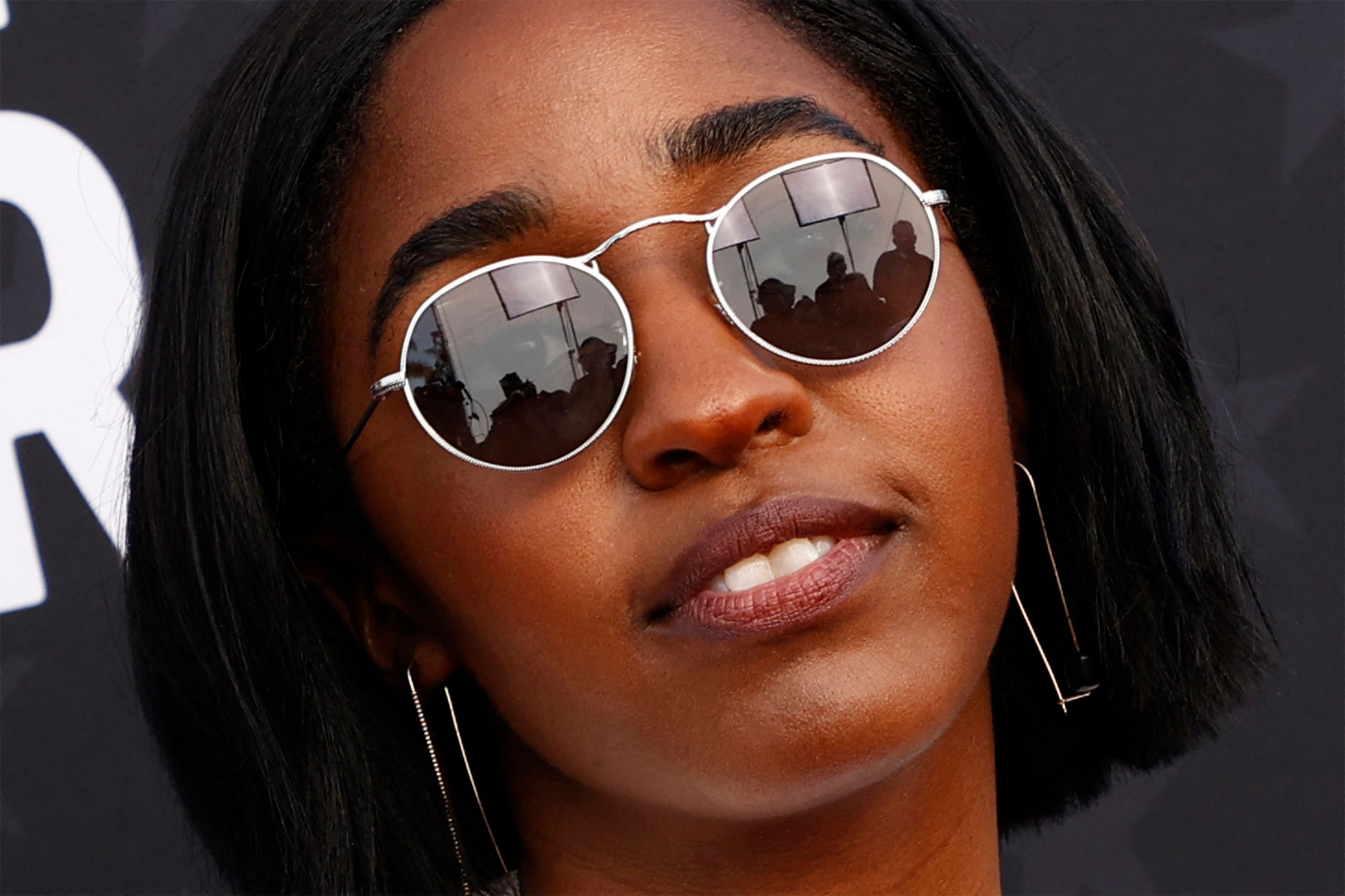 People are seen reflected in Ayo Edebiri's sunglasses on the red carpet.