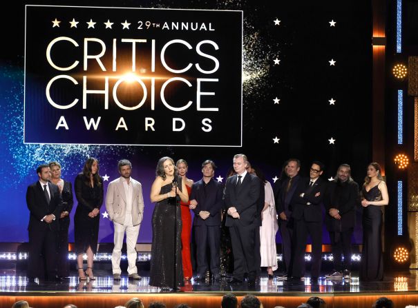 Producer Emma Thomas accepts the best film award for "Oppenheimer," alongside cast and crew members. 