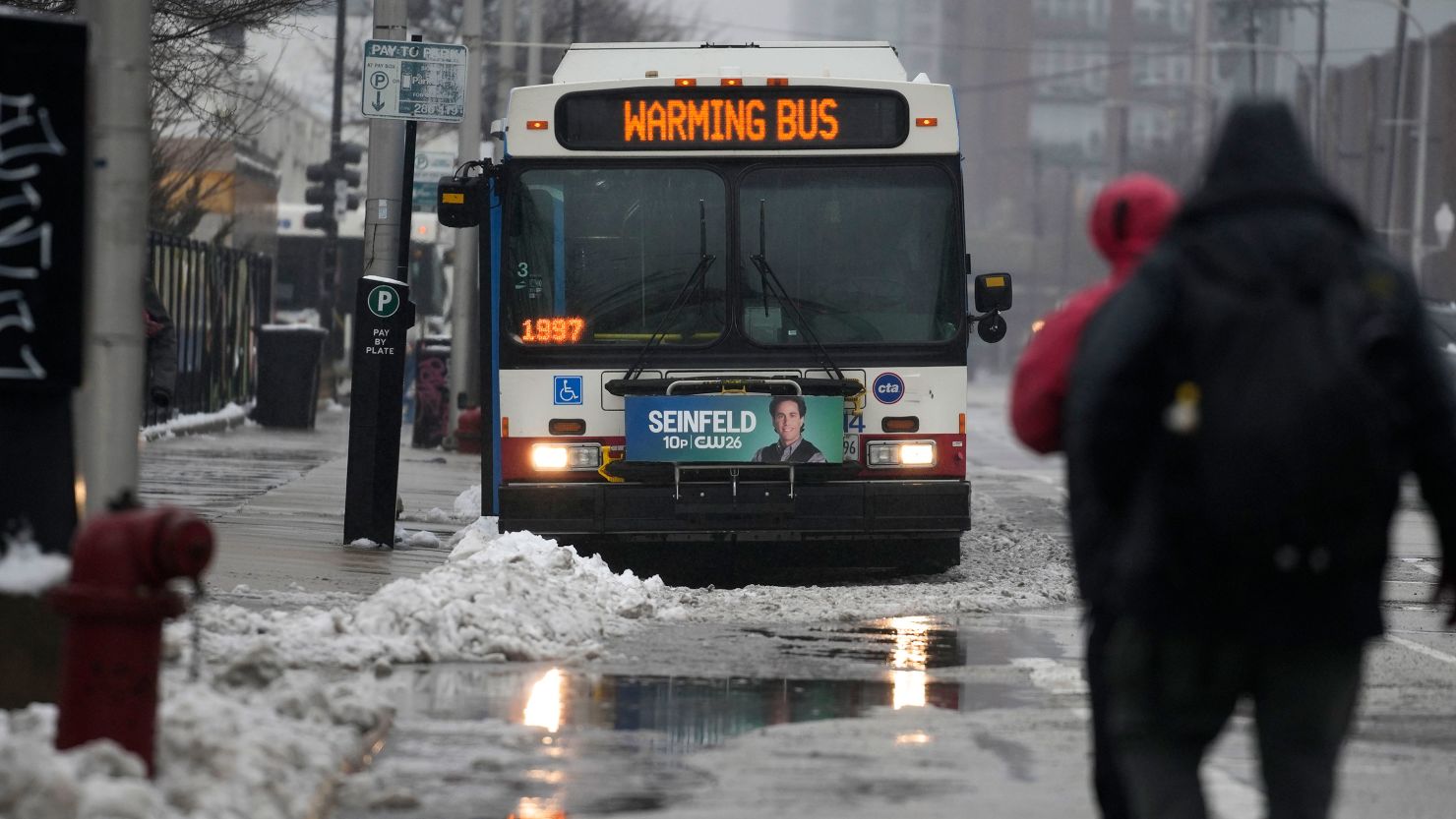 Snow falls as migrants continue to be housed by the city in "warming" buses in the 800 block of South Desplaines Street during a winter storm Friday, Jan. 12, 2024, in Chicago. (AP Photo/Erin Hooley)