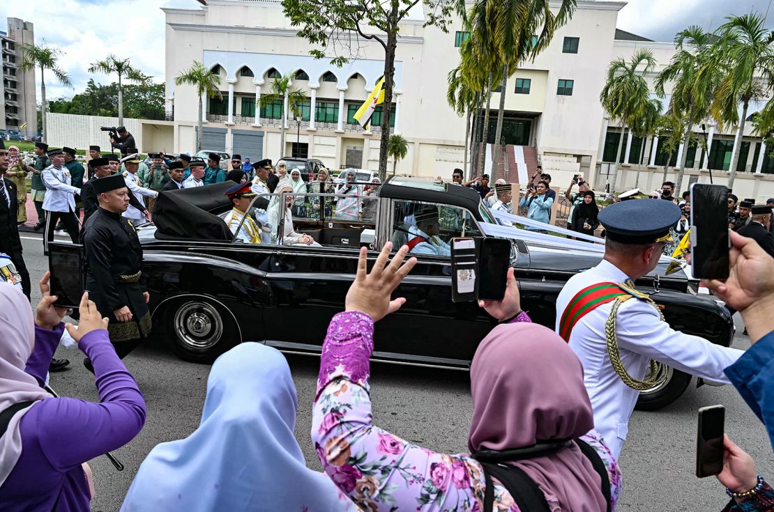People cheer as Prince Abdul Mateen and Yang Mulia Anisha Rosnah sit in their car during the wedding procession in Brunei's capital Bandar Seri Begawan on January 14, 2024.