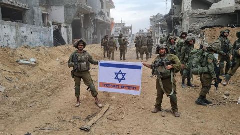 The flag in held by the soldiers in the destroyed street reads: "Coming home!"