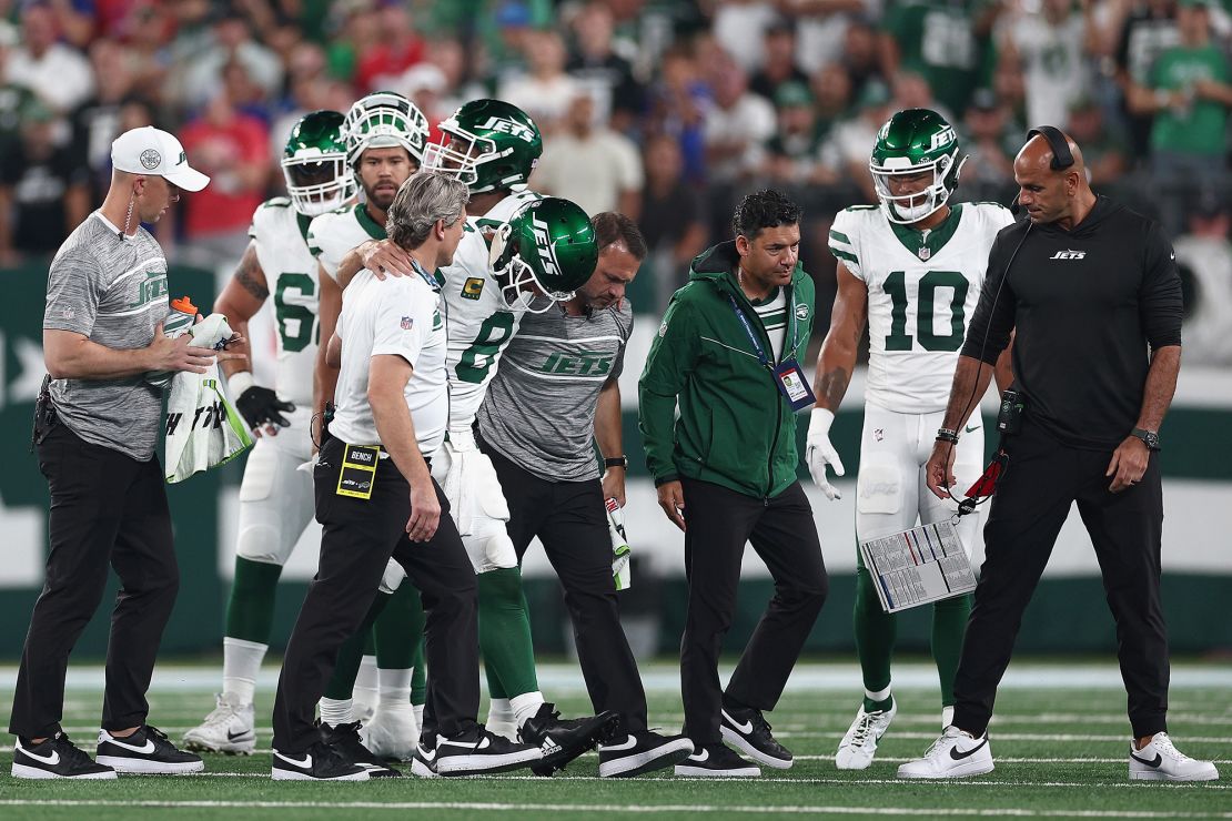 EAST RUTHERFORD, NEW JERSEY - SEPTEMBER 11: Quarterback Aaron Rodgers #8 of the New York Jets is helped off the field by team trainers after an injury during the first quarter of the NFL game against the Buffalo Bills at MetLife Stadium on September 11, 2023 in East Rutherford, New Jersey. (Photo by Elsa/Getty Images)