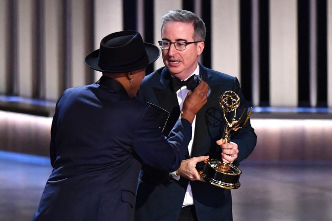 Arsenio Hall adjusts John Oliver's bowtie on stage after "Last Week Tonight with John Oliver" won another Emmy. Oliver collected awards for outstanding scripted variety series and outstanding writing for a variety series.