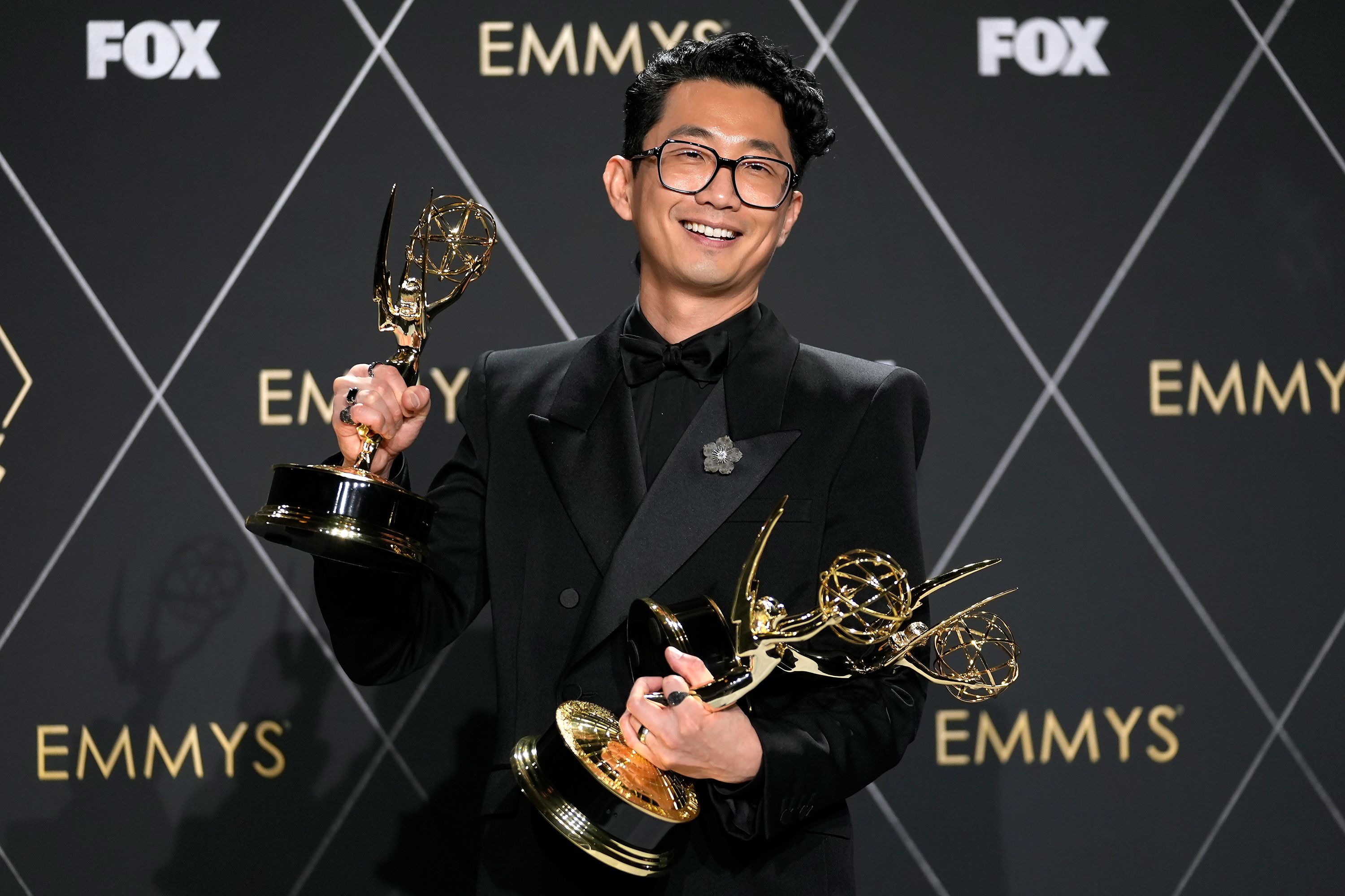 Lee Sung Jin, the creator of the limited series 'Beef,' poses with some of the Emmys the show won on Monday.