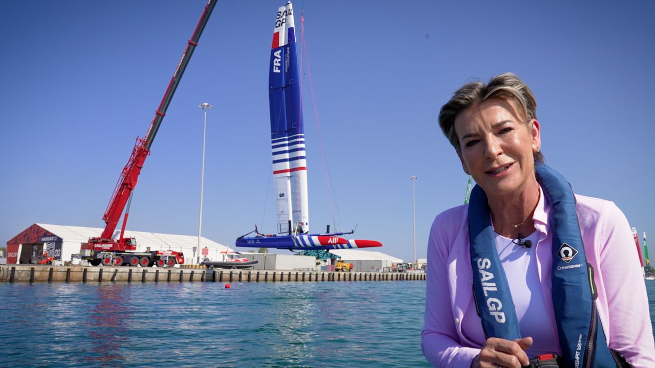 CNN's Becky Anderson at the Abu Dhabi Sail Grand Prix while an F50 catamaran is winched into the water behind her. 
