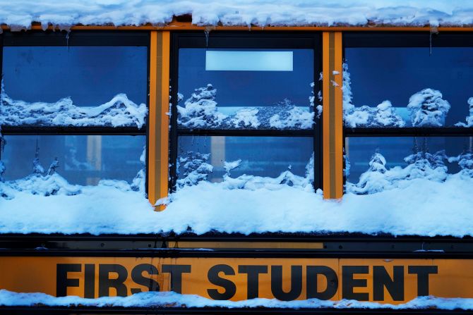 A snow-covered school bus sits in a parking lot in Wheeling, Illinois on January 16. School districts in more than half a dozen states announced closures amid frigid temperatures.