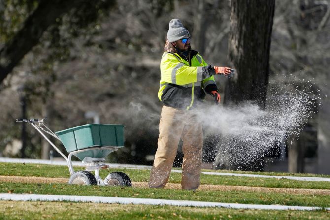 A worker spreads a composite of ice melter and salt on sidewalks at the Mississippi State Capitol in Jackson on January 16.