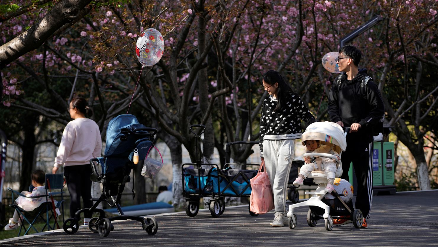 A parents pushes a stroller with a baby in a park in Shanghai, China, April 2, 2023. REUTERS/Aly Song